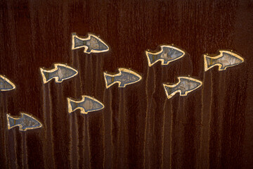 Fish shaped cutouts in a rusted steel plate