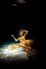 Fototapeta premium A graceful underwater pose shows a dancer with flowing fabric, blending elegance in art