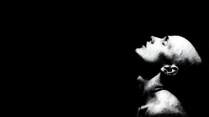 Fototapeta premium High contrast stark image of a bald person looking upward in shadow and light