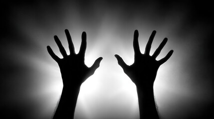 Silhouette of two hands reaching upward in a dimly lit space