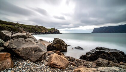 Dramatic seascape with smooth ocean waves crashing on a rocky shore under a cloudy sky on a cool day