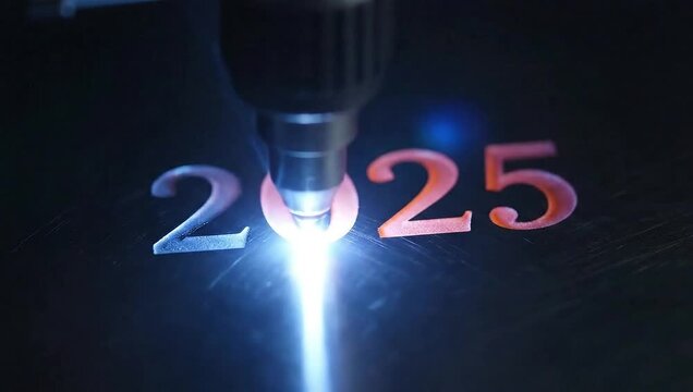 A laser beam etches the number '2025' onto a dark metal plate. It then glows red-hot and is overwritten by the laser etching '2026' over it