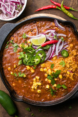 Chili con carne on wooden table with corn and spices