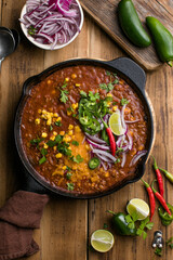 Chili con carne on wooden table with corn and spices