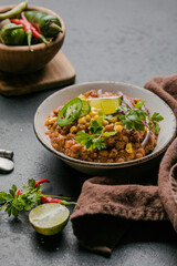 Chili con carne on wooden table with corn and spices