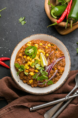 Chili con carne on wooden table with corn and spices
