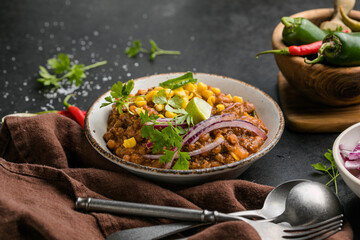 Chili con carne on wooden table with corn and spices