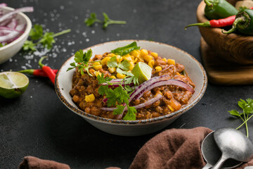 Chili con carne on wooden table with corn and spices