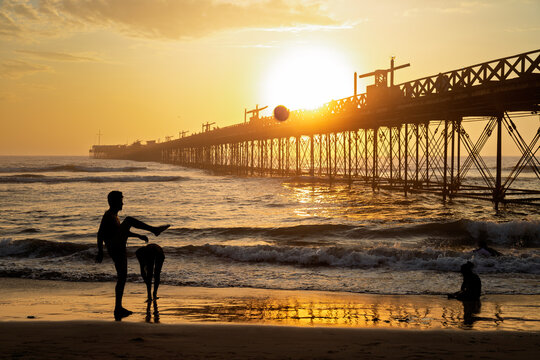 Man playing soccer on the beach with two girls at sunset in Pimentel, Peru - Powered by Adobe