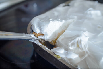 Homemade Cremeschnitte in a pan made and a knife that cuts a piece of cake.