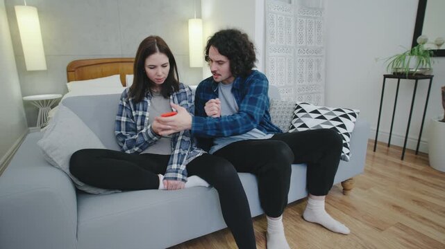 A man glances at his partner s phone as she texts, then grabs it and starts arguing. The scene captures rising tension and mistrust in a modern relationship