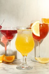 Glasses of tasty cocktails with garnish on white marble table, closeup