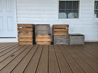 Rustic wooden crates on a wooden porch in front of white wall