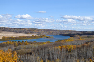 Obraz premium river in autumn with blue sky and white fluffy clouds 