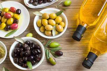 Olive varieties from Turkish Cuisine designed on white plates at a wooden surface. with two bottles...