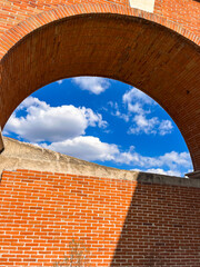Red brick arch framing vivid blue sky and clouds