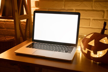 Laptop with a blank white screen mockup with space for text on a wooden table in evening dark room...