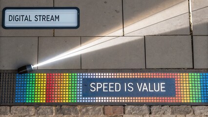 Bright colorful sidewalk mural with text message about value of speed in digital age using light projection