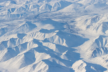 Aerial view of snow-capped mountains. Winter snowy mountain landscape. Air travel to the far North of Russia. Khal-Urekchen ridge, Kolyma Mountains, Magadan Region, Siberia, Russian Far East.