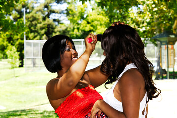 One African American Woman Outdoors Brushing The Hair Of Another One