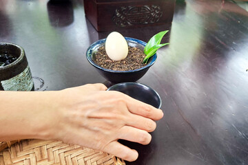 Close Up Of A Hand Reaching For A Small Dessert With A Scoop Of Egg And A Green Garnish