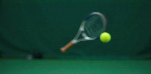 Tennis racket and ball in motion on a court, dynamic blur effect, representing speed and action. A dynamic, close up shot of a tennis racket mid swing, blurring as it strikes a tennis ball. The