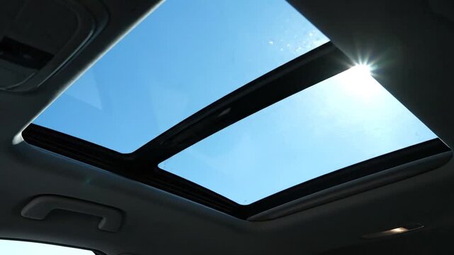 Dynamic Car Sunroof Opening to Bright Blue Sky with Dazzling Sun Flare on a Sunny Journey