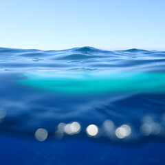 Underwater view of the ocean with clear blue water and sunlight creating bokeh effect