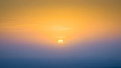 Golden sunrise over a misty horizon, casting a warm glow on the serene and tranquil landscape