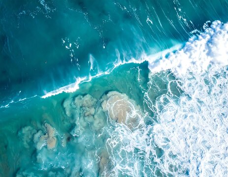 Aerial view showing the ocean waves crashing on the shore with turquoise water