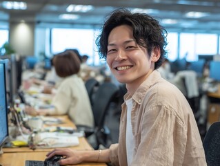 オフィスで笑顔を見せるカジュアルな服装の若い男性会社員のポートレート