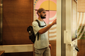 Young man using a digital self-service kiosk to place an order in fast food restaurant. Concept of technology, modern lifestyle, and convenience