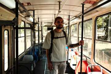 Young man standing inside an old city tram holding a pole. Concept of urban transport, nostalgia, and daily commute