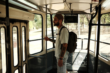 Young man standing inside an old city tram holding a pole. Concept of urban transport, nostalgia, and daily commute