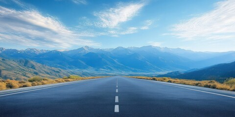 Obraz premium Long straight empty road leading towards distant blue mountains under a bright sky with scattered clouds evoking calm and freedom