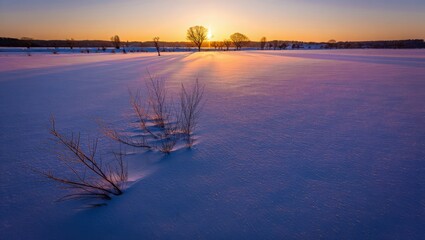 Winter sunset over frozen landscape with rays of light