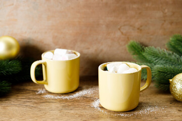 Hot chocolate in yellow cup on wooden table background.