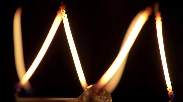 Closeup of a vintage Edison light bulbs glowing filament showcasing the intricate spiral design and warm inviting light against a dark background symbolizing ideas and innovation.