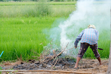 A woman is lighting a pile of garbage on fire.