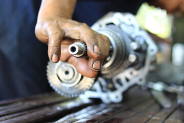 The hands of a mechanic repairing a car transmission.