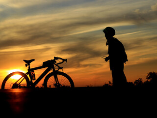 The silhouette of a person and a bicycle during a beautiful sunset.