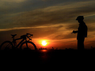 The silhouette of a person and a bicycle during a beautiful sunset.