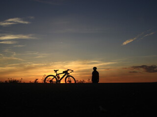 The silhouette of a person and a bicycle during a beautiful sunset.