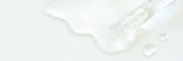 Clear liquid droplets and pipette on white surface representing skincare and cosmetic research.