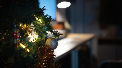 Close-up Christmas tree with glowing lights beside cozy home office at night