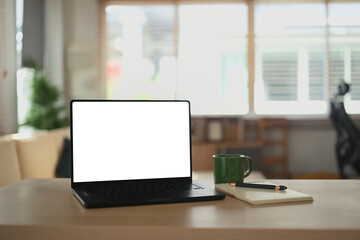 Photo of white blank screen laptop, coffee cup on working desk