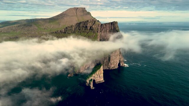 Dramatic cliffs of Drangarnir emerge from the Atlantic Ocean, surrounded by mist and waves. This breathtaking location in the Faroe Islands offers a perfect blend of rugged beauty and tranquility.