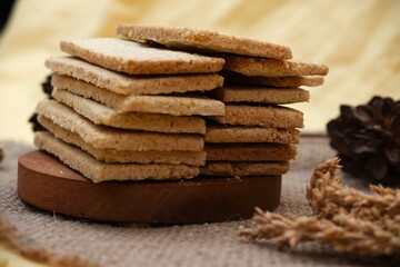 Classic Indonesian sagon cookies made from roasted coconut and flour, stacked in a wooden bowl on burlap with natural elements.	