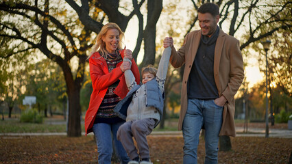 Family enjoying a fun day at the park in autumn with their young son
