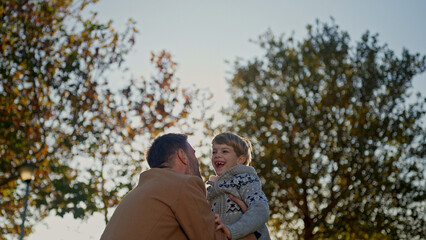 Fototapeta premium Father and son laughing together in a park on a sunny autumn day